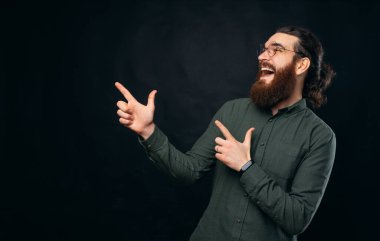 Kendinden geçmiş sakallı erkek hippi gülümserken iki elini de kaldırıyor. Stüdyo çekimi siyah arkaplan üzerinde.