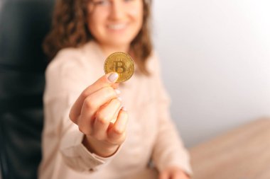 Kameraya altın bir Bitcoin gösteren genç bir kadının resmi yok. Bulanık arkaplan.