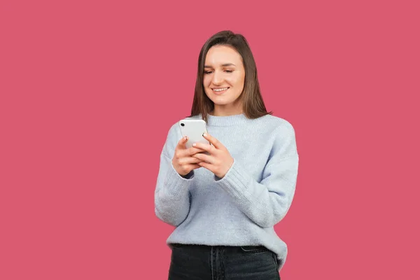 Positieve Jonge Vrouw Houdt Haar Telefoon Vast Typt Iets Studio — Stockfoto
