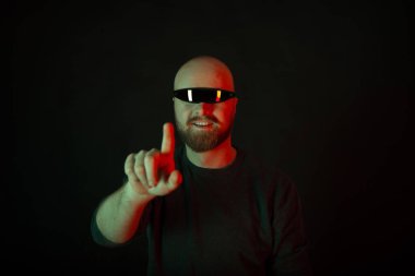 Ciclop güneş gözlüğü takan gülümseyen genç adam kamerayı işaret ediyor..