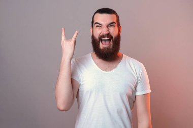 Mest olmuş sakallı adam kameraya bağırırken taş hareketi yapıyor..