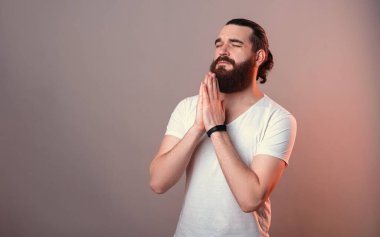 Gözleri kapalı, sadık sakallı adam dua etmek için el ele tutuşuyor..
