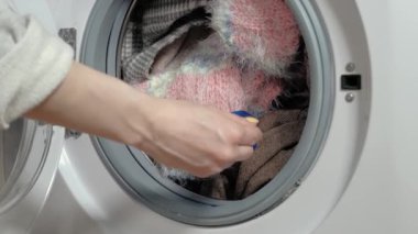 Çamaşır makinesine çamaşır koyan kadının görüntülerini kapat.