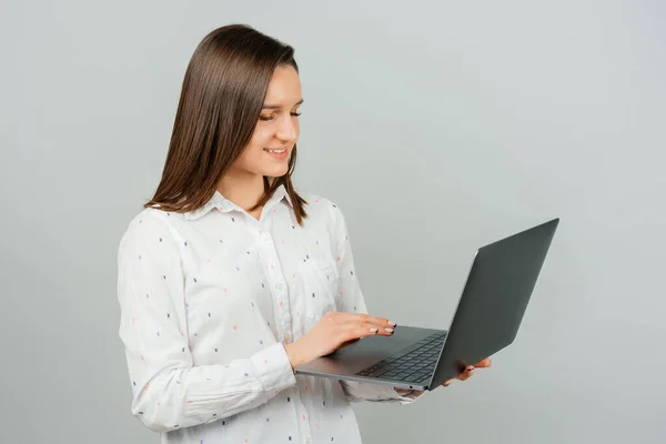 Intelligente giovane bruna donna è in possesso di un computer portatile e digitando qualcosa su di esso. — Foto Stock