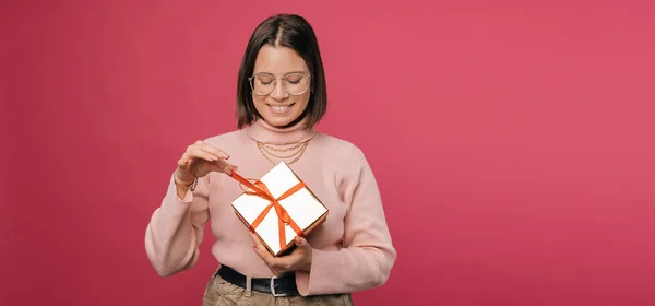 Panorama photo rose d'une jeune femme déballer un cadeau qu'elle a reçu. — Photo