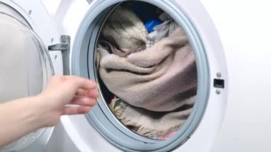 Çamaşır makinesinden temiz çamaşır çıkartan kadının görüntülerini kapatın.