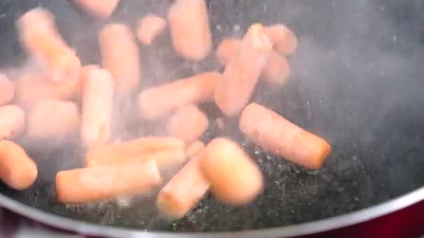 Nahaufnahme der Zubereitung einiger gefrorener Baby-Karotten in der Pfanne — Stockvideo