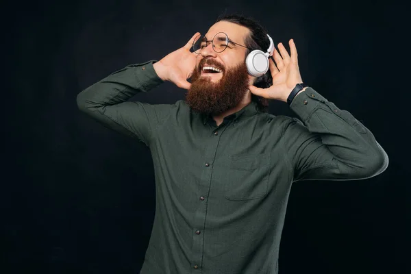 Barbudo hombre está teniendo un buen momento mientras escucha la música ingenio auriculares. —  Fotos de Stock