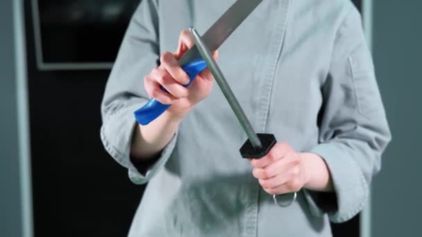 Kadın şefin mutfak bıçağını keskinleştirdiği görüntüleri kapat. — Stok video