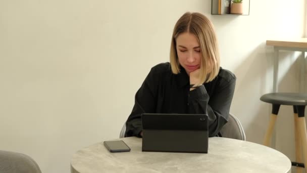 Happy young woman working on tablet in cafe and smiling — стоковое видео