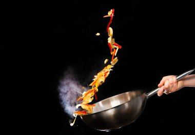 Şefin siyah arka plan üzerine sebze karıştırma fotoğrafını kapat..