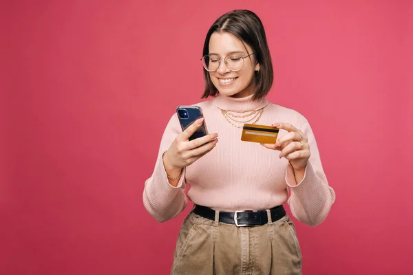 Smiling Woman Using Mobile Banking While Holding Her Phone Card — стоковое фото