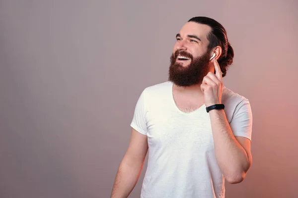 Cheerful Bearded Man Touching Ear Pod Wearing While Laughing Studio — 스톡 사진