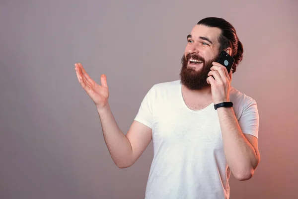 Kedves Szakállas Férfi Beszél Telefonon Miközben Gesztikulál Stúdióban Szürke Háttérrel — Stock Fotó