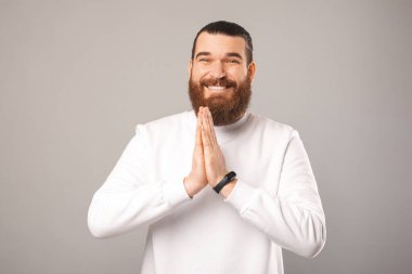 Sevimli gülümseyen genç sakallı adam dua etmek için el ele tutuşuyor..