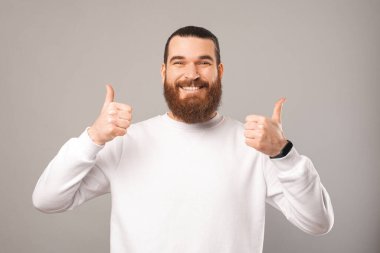 Dost canlısı sakallı adam kameraya gülümserken iki parmağını kaldırıyor..
