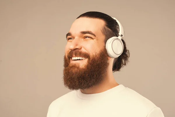 Close up photo of a joyful bearded man enjoys music and his earphones. — Fotografia de Stock