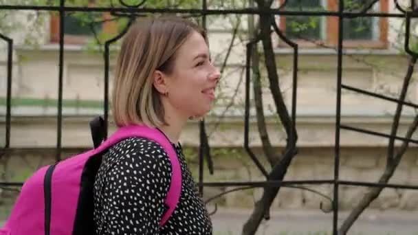 閉じますアップフッテージの若いです女性とともにピンクのバックパック歩く上のヨーロッパの通り — ストック動画