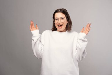 Genç kısa saçlı kız bir stüdyoda jest yapıyor ve şaşkın şaşkın bakıyor..