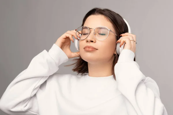 Jovem mulher usando óculos e fones de ouvido gosta de música e seu tempo sozinho. — Fotografia de Stock