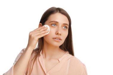 Mavi gözlü sarışın bir kadın pamukla makyajını temizliyor..