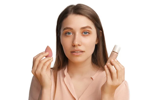 Beautiful woman is holding a sponge blender and make up foundation. — 스톡 사진