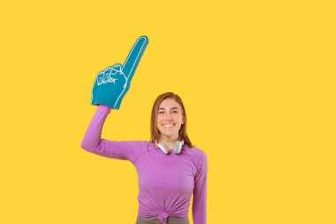 Spor giyim ve köpük yelpaze eldiven giyen genç bir kadının uzay fotoğrafını kopyala.