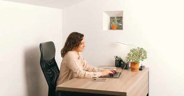 Photo of young woman in casual siting and working at desk on laptop — Stockfoto