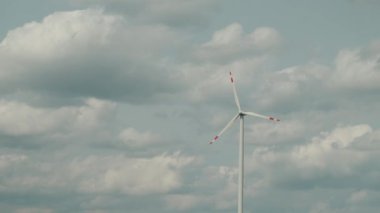 Alternatif enerji için rüzgar türbini görüntülerini güzel bulutlu gökyüzünde yavaş çekimde kapat