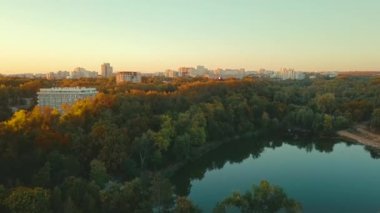 Aerial drone video of lake and forest in middle of city during sunset