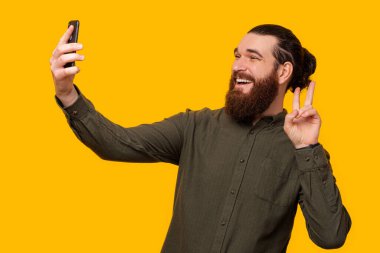 Sakallı adam telefonuyla fotoğrafını çekerken Ziyaretçi jesti yapıyor..