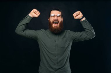 Güçlü sakallı adam, kazanan hareketi yaparken geniş çığlıklar atıyor..