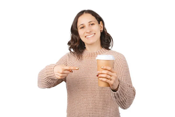 Cheerful woman is pointing at a take away paper cup she is holding. — Stock Photo, Image