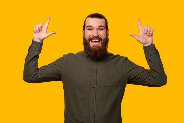 Portrait d'un homme barbu pointant vers le haut avec les deux mains à l'espace de copie. — Photo