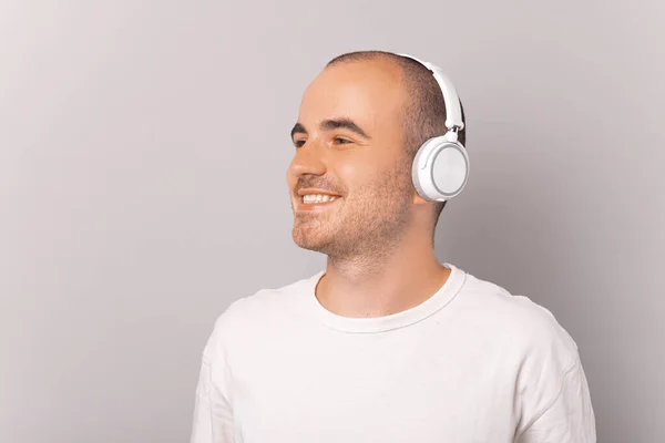 Portrait Young Man Smiling Listening Music While Looking Away Grey — Φωτογραφία Αρχείου