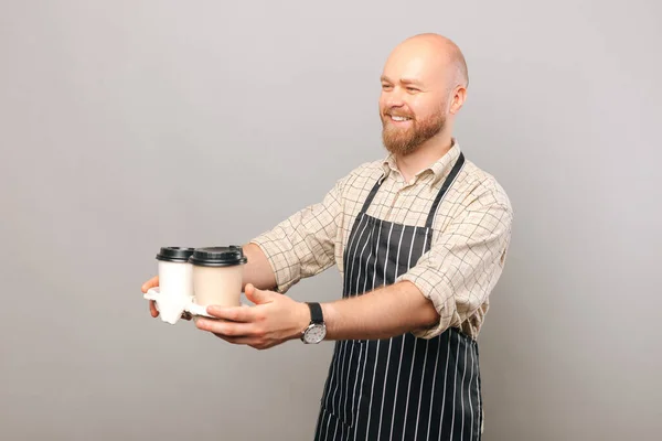 Photo Barista Giving Someone While Smiling Two Cups Coffee Grey — стоковое фото