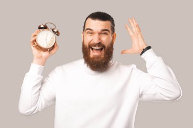 Saat tutan heyecanlı sakallı bir adamın fotoğrafı.