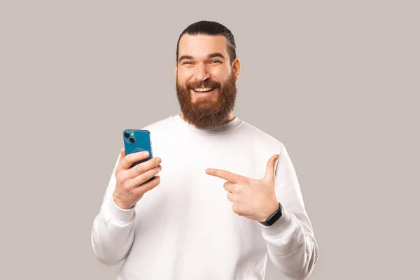 Photo Bearded Man Pointing His Phone While Looking Camera Smiling — Stockfoto