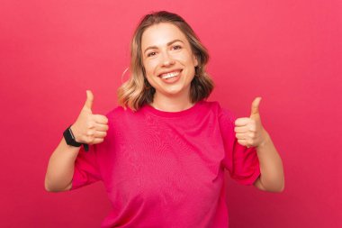 Başparmağıyla kameraya gülümseyen genç bir kızın fotoğrafı.