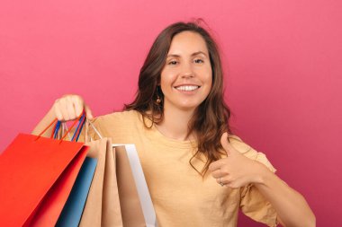 A picture of a young woman holding some shopping bags and her being happy and thankful about it 