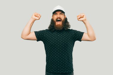 A picture of a bearded man screming and being angry while looking at the camera and holding his hands up