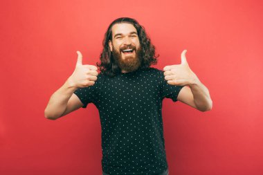 A photo of happy young man showing thumbs up while smiling at the camera