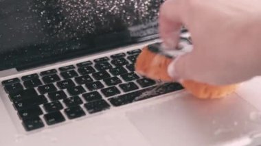 Close up footage of male hand cleaning with soap and sponge laptop.