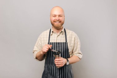 A photo of a young barista grinding coffee beans and cheerfuly looking at the camera