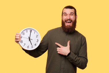 A picture of a man holding a white clock while hes smiling