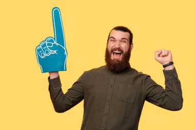 A picture of a young man holding a blue fan glove screaming of hapiness