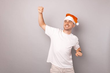  A picture of a young man that is dancing while he is wearng a christmas hat