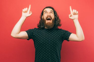 An excited bearded man is pointing with his both hands up at a promotion