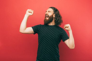 A bearded man cheerfuly is dancing in front of camera laughing