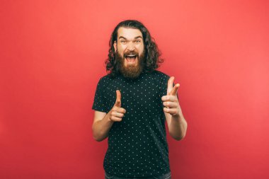 A bearded man is pointing alarmly at the camera while screaming excitingly